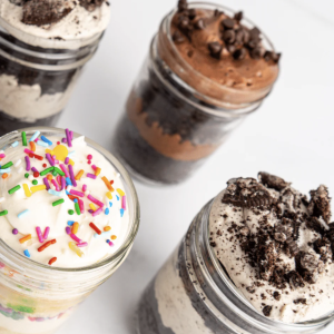 Dozen 8oz cake jars with layered moist cake, creamy frosting, and decadent fillings.