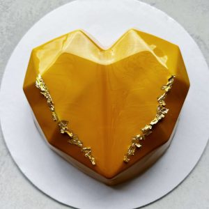 Heart-shaped custom mousse cake with mirror glaze and gold accents.